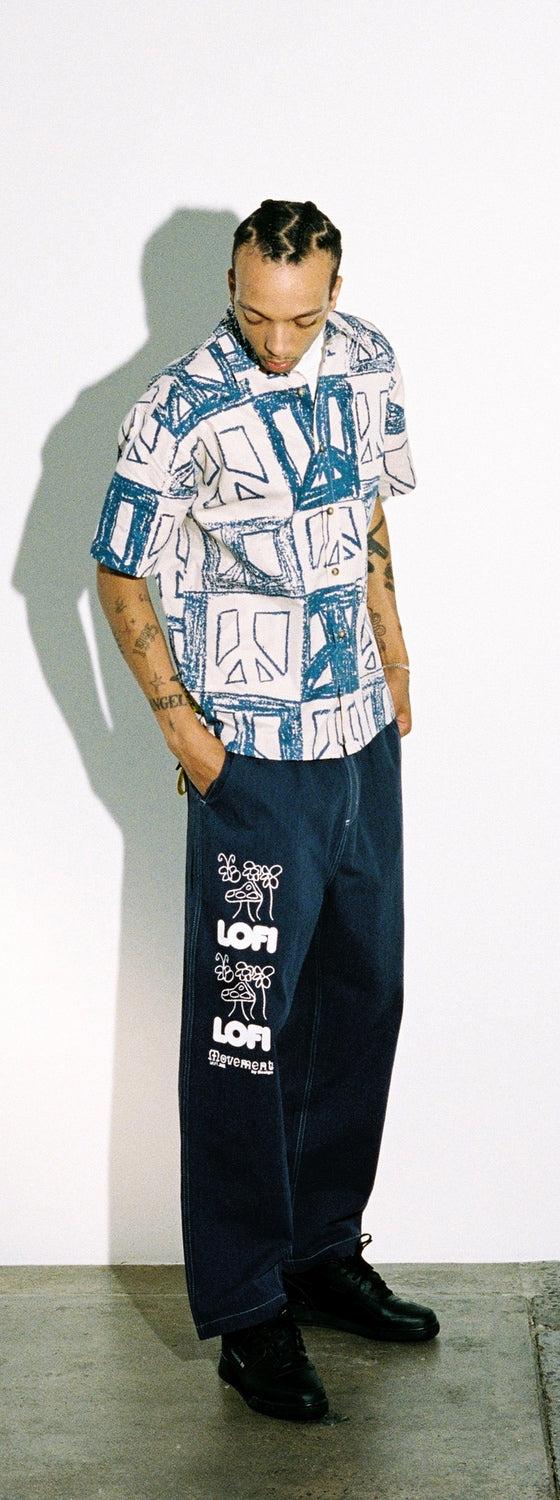 A man wearing a blue-printed Lo-fi camp-collar shirt with wide dark denim jeans