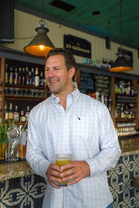 A man wearing a pastel plaid Local Boy Outfitters button-down shirt at a bar