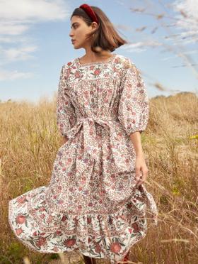 A woman wearing a floral-print tiered midi dress with puff sleeves and a red headband