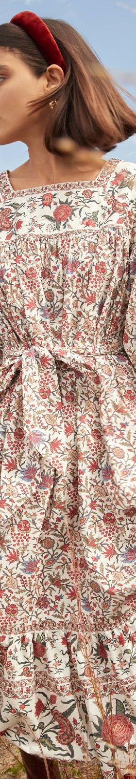 A woman wearing a floral-print tiered midi dress with puff sleeves and a red headband