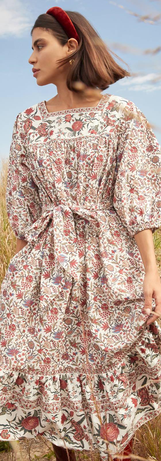 A woman wearing a floral-print tiered midi dress with puff sleeves and a red headband