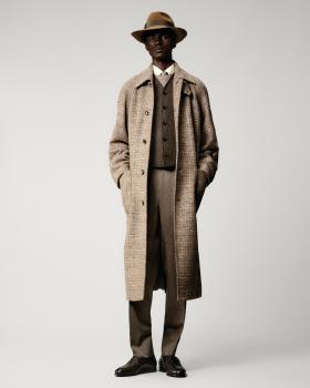 A man wearing a checked wool Loro Piana overcoat with matching tailored trousers and a felt hat