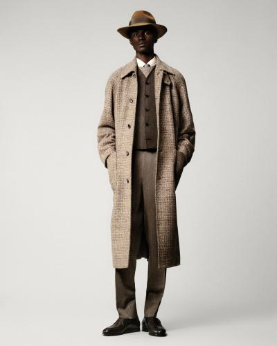 A man wearing a checked wool Loro Piana overcoat with matching tailored trousers and a felt hat