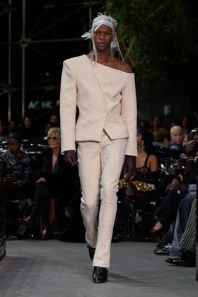 A model wearing a cream Luar asymmetric off-the-shoulder blazer and matching trousers on the runway