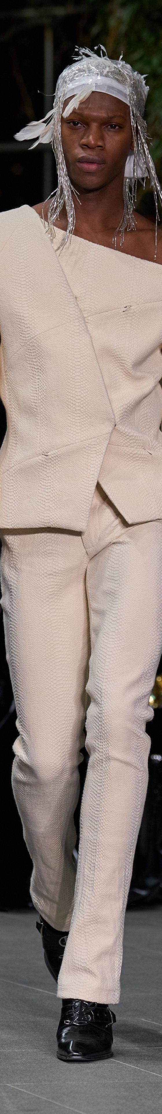 A model wearing a cream Luar asymmetric off-the-shoulder blazer and matching trousers on the runway