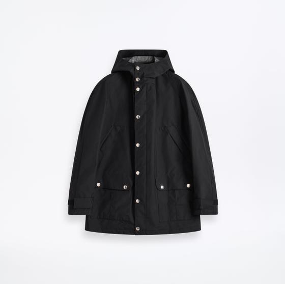 A black Mackintosh hooded raincoat with press-stud fastening on a plain white background