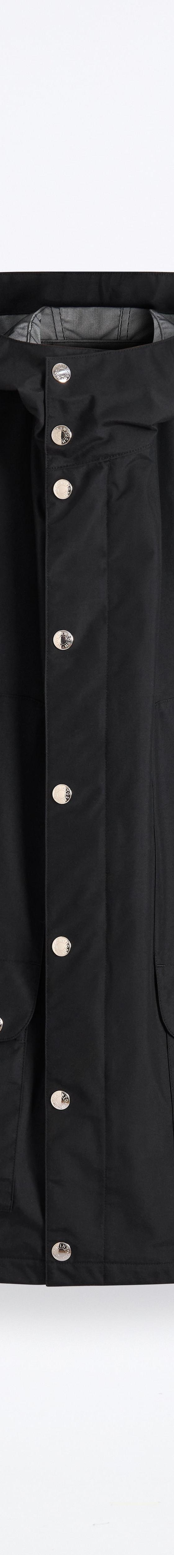 A black Mackintosh hooded raincoat with press-stud fastening on a plain white background