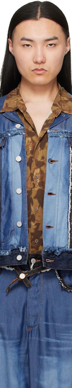 A man wearing a patchwork blue denim Magliano jacket with a printed brown shirt and matching jeans
