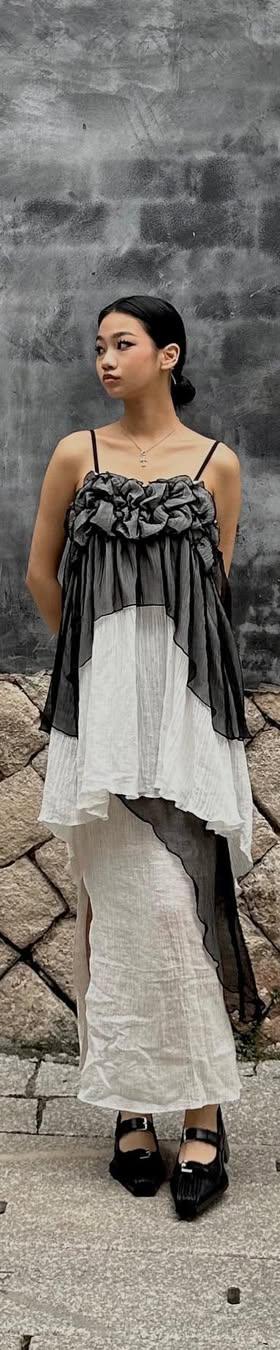 A woman wearing a ruched grey and ivory Maison Mume camisole top over a long white slip skirt