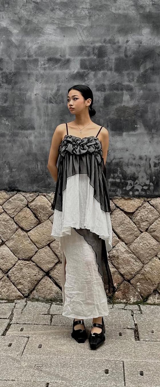 A woman wearing a ruched grey and ivory Maison Mume camisole top over a long white slip skirt