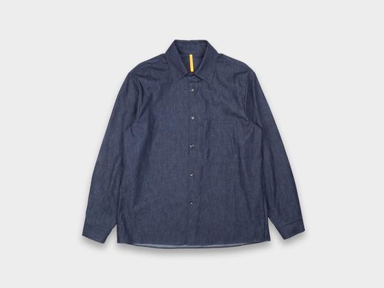 A dark indigo MAN-TLE button-up shirt with a chest pocket, shown on a plain light grey background