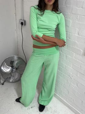 A woman wearing a mint green Many Many Clothes top and matching wide-leg trousers
