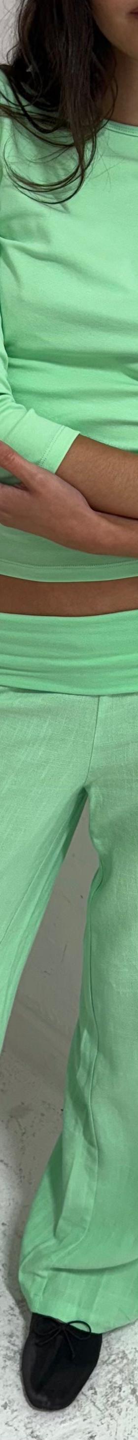 A woman wearing a mint green Many Many Clothes top and matching wide-leg trousers