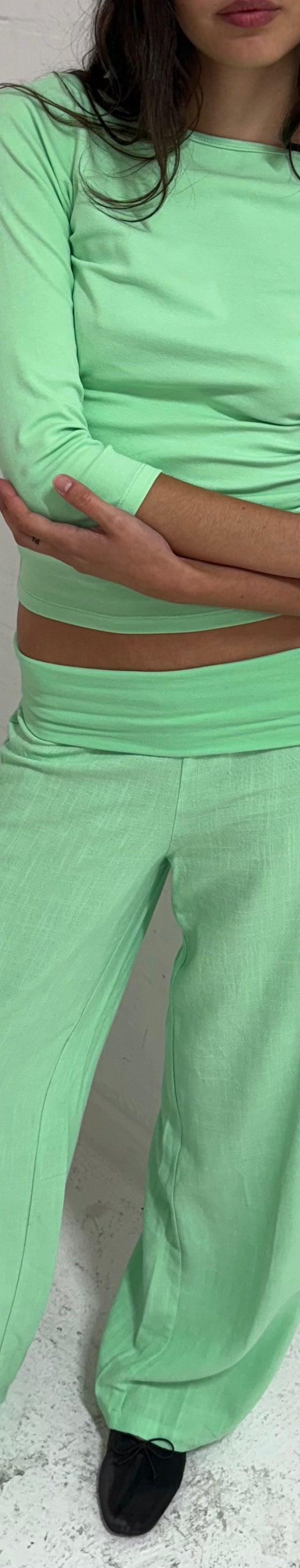A woman wearing a mint green Many Many Clothes top and matching wide-leg trousers