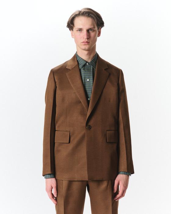 A man wearing a brown MARKAWARE tailored jacket over a green check shirt