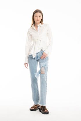 A woman wearing a white tie-front Marques'Almeida shirt with distressed frayed-hem jeans and leopard-print sandals