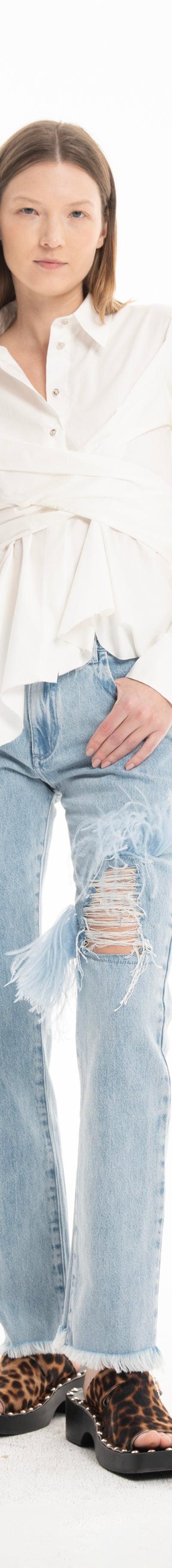 A woman wearing a white tie-front Marques'Almeida shirt with distressed frayed-hem jeans and leopard-print sandals