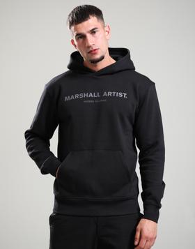 A man wearing a black Marshall Artist logo hoodie