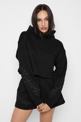 A woman wearing a black Mary Wyatt London cropped hoodie and matching shorts