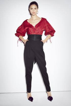 A woman wearing a red puff-sleeve blouse and high-waisted black trousers