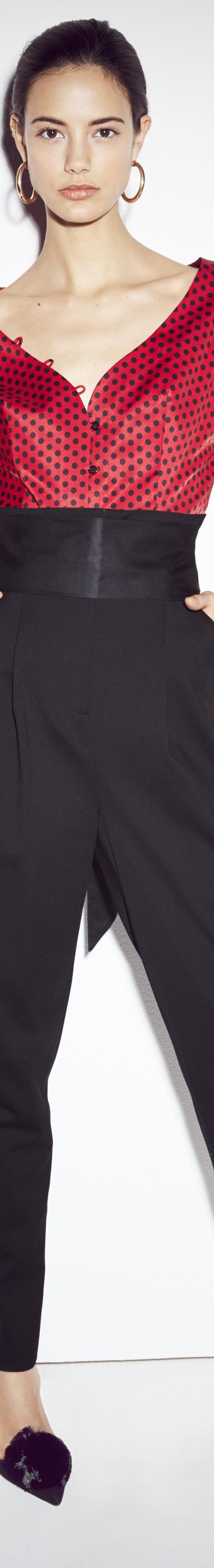 A woman wearing a red puff-sleeve blouse and high-waisted black trousers