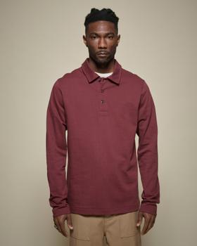 A man wearing a burgundy Merz b. Schwanen long-sleeve knit polo with tan trousers