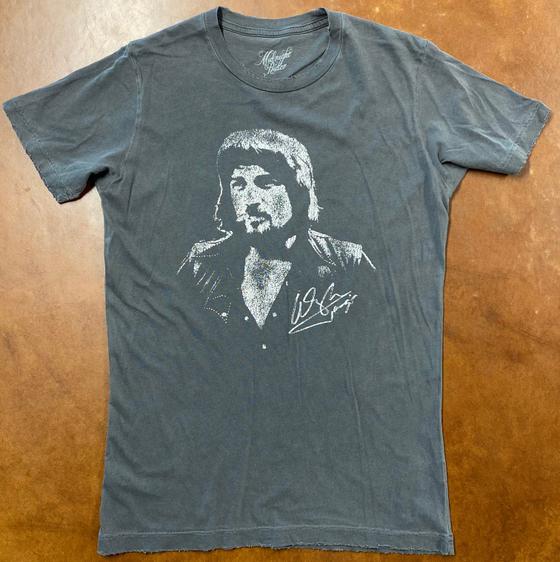 A faded blue Midnight Rider graphic t-shirt laid flat on a brown leather surface