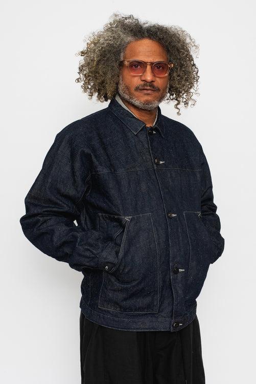 A man wearing an indigo MITTAN denim jacket with dark trousers