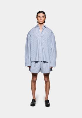 A man wearing a blue striped MKI Miyuki Zoku oversized shirt and matching shorts