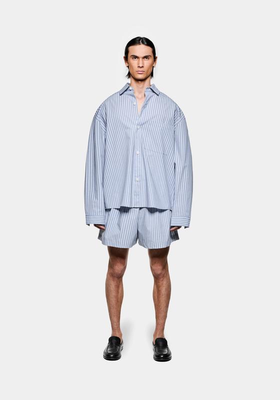 A man wearing a blue striped MKI Miyuki Zoku oversized shirt and matching shorts