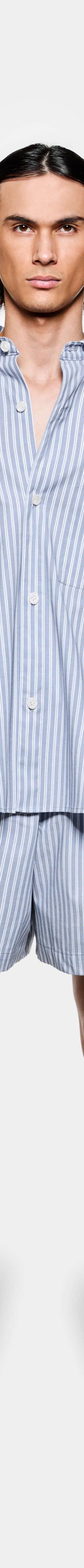 A man wearing a blue striped MKI Miyuki Zoku oversized shirt and matching shorts