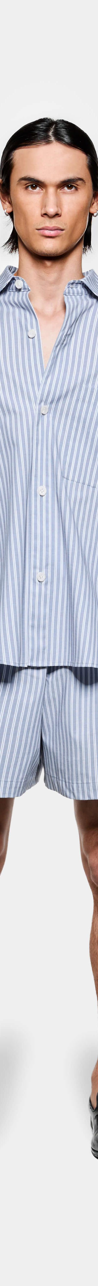 A man wearing a blue striped MKI Miyuki Zoku oversized shirt and matching shorts