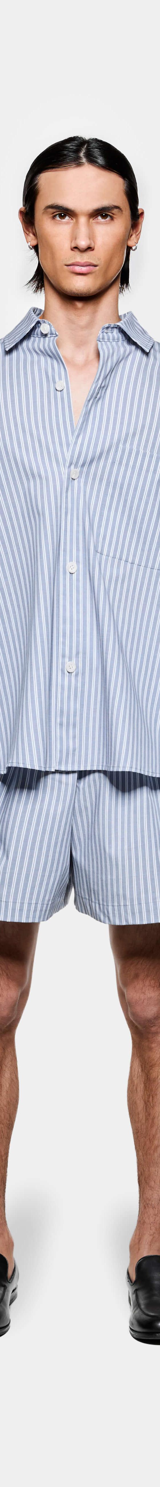A man wearing a blue striped MKI Miyuki Zoku oversized shirt and matching shorts