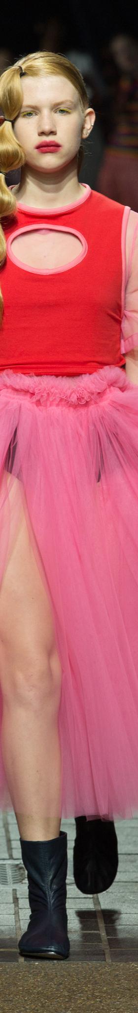 A model wearing a voluminous pink tulle Molly Goddard skirt with a red top on the runway