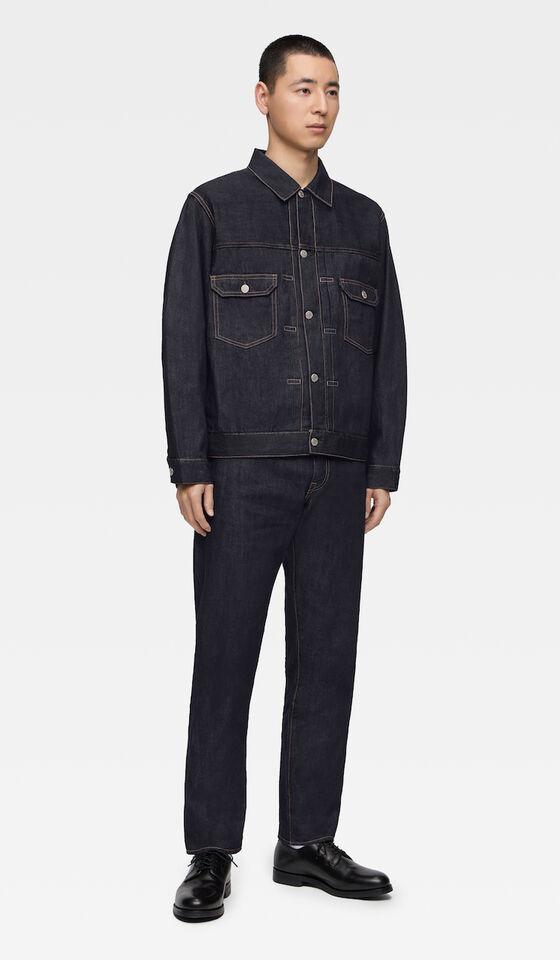 A man wearing a raw indigo Momotaro Jeans denim jacket and matching selvedge jeans