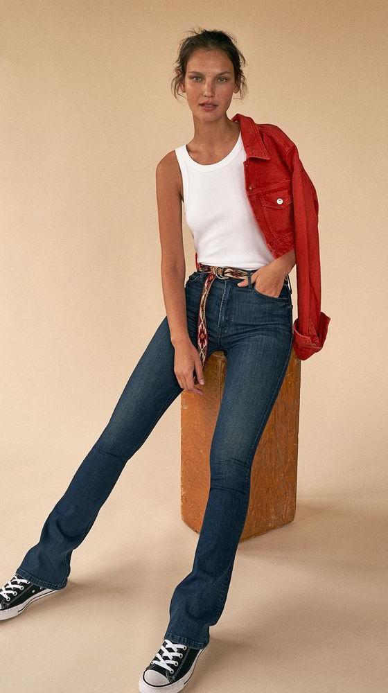 A woman wearing MOTHER Denim bootcut jeans with a white tank and red denim jacket