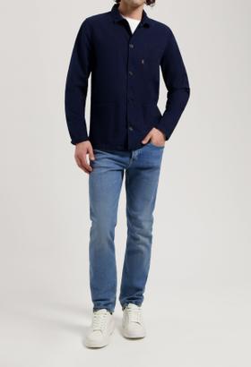 A man wearing a navy MUD Jeans overshirt and light blue jeans