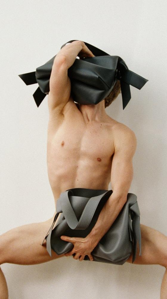 A model holding knotted grey Musubi wrapping-cloth bags