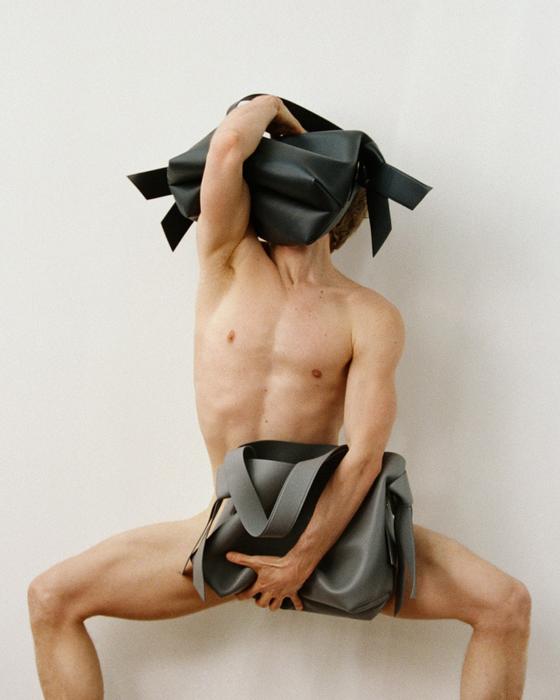 A model holding knotted grey Musubi wrapping-cloth bags