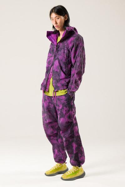 A man wearing a purple garment-dyed NEMEN hooded jacket and matching trousers
