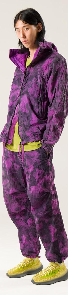 A man wearing a purple garment-dyed NEMEN hooded jacket and matching trousers