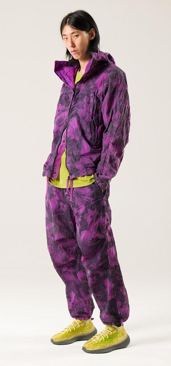 A man wearing a purple garment-dyed NEMEN hooded jacket and matching trousers