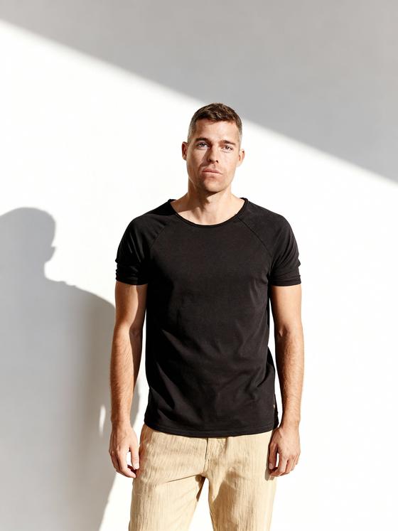 A man wearing a black Nero Cento raglan T-shirt