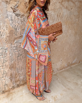 A woman wearing a bold scarf-print Never Fully Dressed maxi dress with a leopard-print clutch