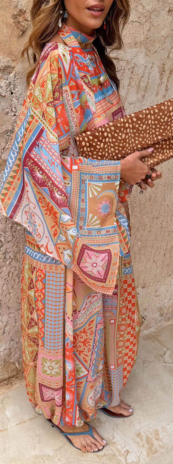 A woman wearing a bold scarf-print Never Fully Dressed maxi dress with a leopard-print clutch