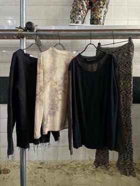New arrivals (knits, a printed top, trousers) hanging on a rail against the white tiles of the former bathhouse