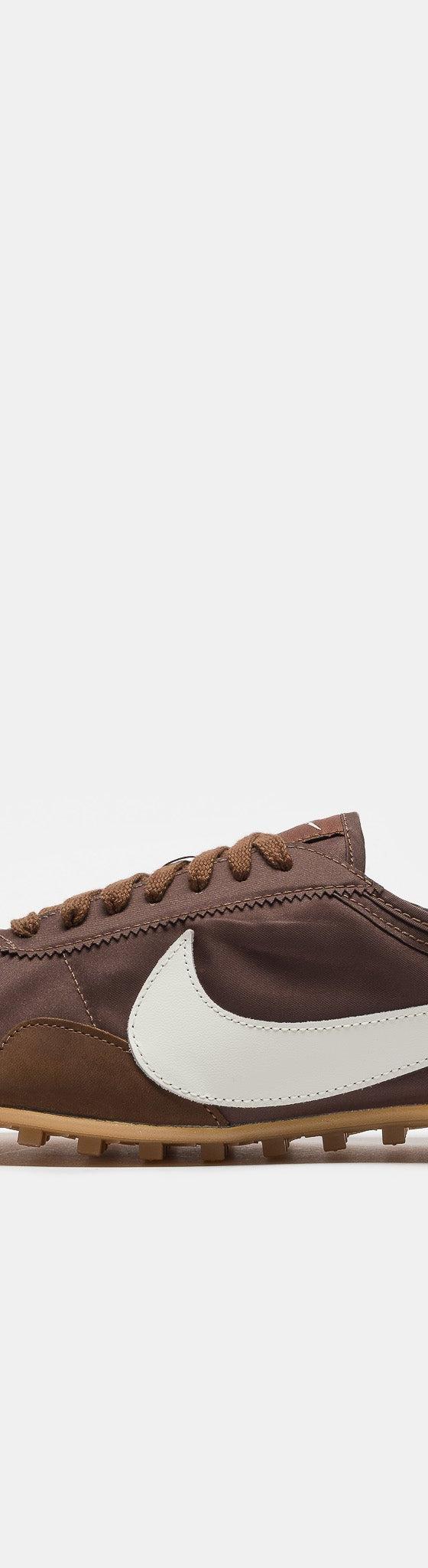 A brown suede and nylon Nike sneaker with a cream swoosh and gum sole