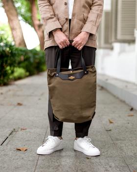 A man holding an olive canvas and leather tote bag from Obbi Good Label