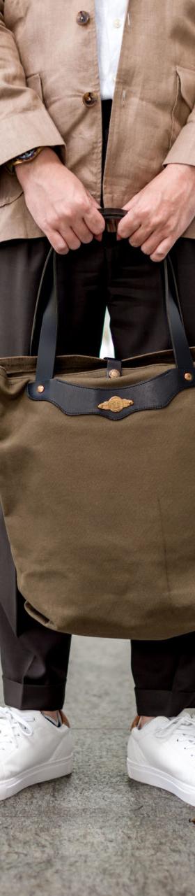 A man holding an olive canvas and leather tote bag from Obbi Good Label