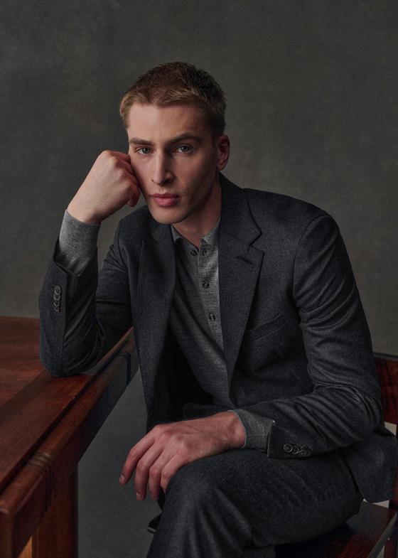 A man wearing a charcoal Octobre Éditions jacket over a grey henley